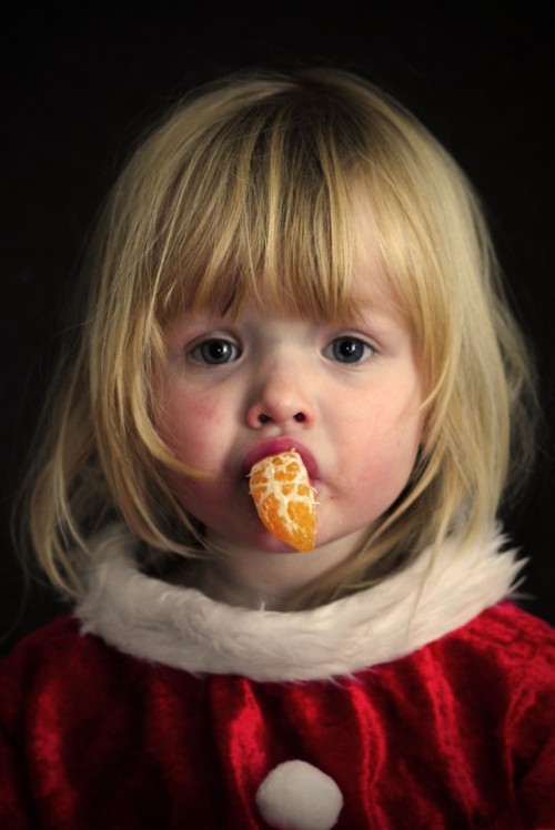 Girl is eating orange with her own style.
