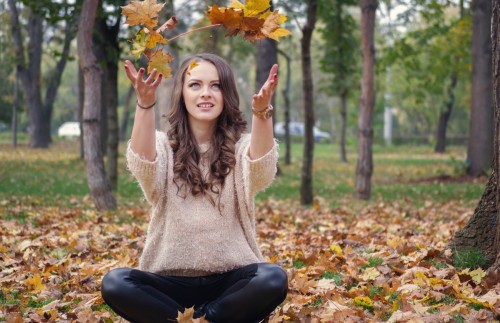 Beautiful girl in the park throwing leaves