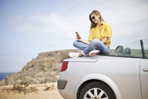 Woman Taking Selfie While Sitting On Car
