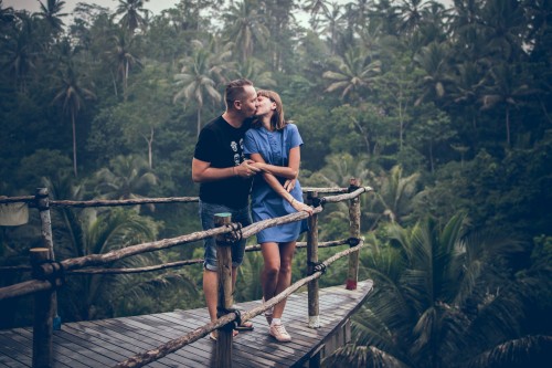 A couple kissing each other standing on the wooden bridge