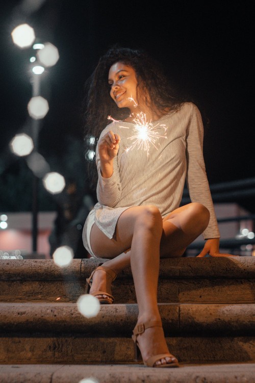Woman Sitting On Concrete Stairs Holding Sparkler