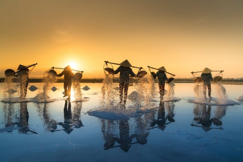 People-pouring-sea-water-on-salt-field-during-sunset
